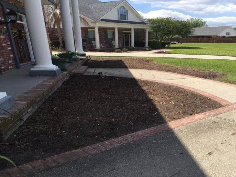 Prepared soil bed ready for planting within a brick-bordered garden space, at a residential home serviced by Eric's Tidy Turf.