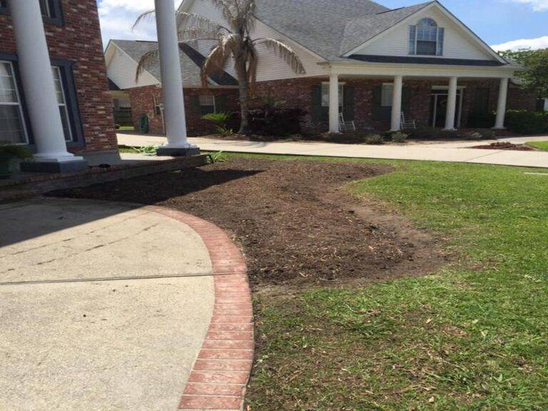 Prepared soil bed ready for planting within a brick-bordered garden space, at a residential home serviced by Eric's Tidy Turf.